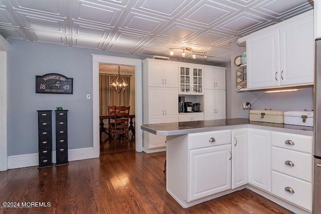 kitchen featuring white cabinetry, kitchen peninsula, dark wood-type flooring, and a notable chandelier