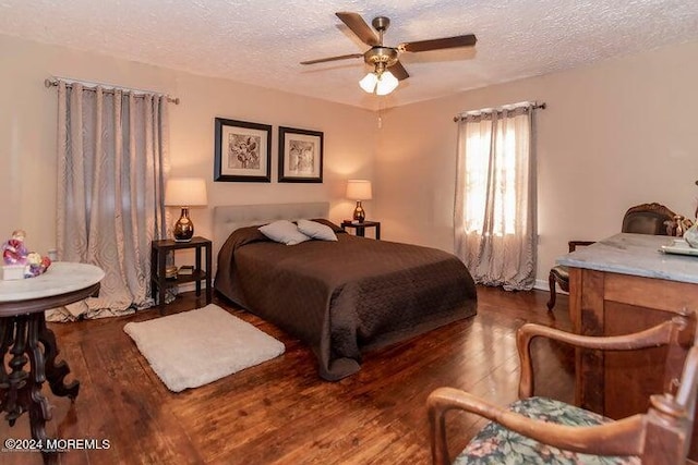 bedroom with ceiling fan, dark hardwood / wood-style floors, and a textured ceiling