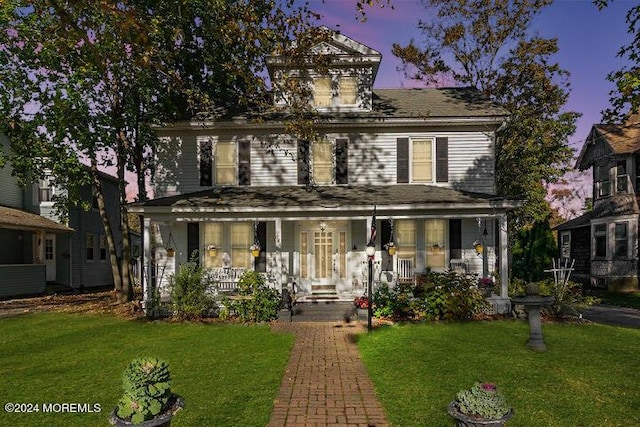 view of front of property with a porch and a yard