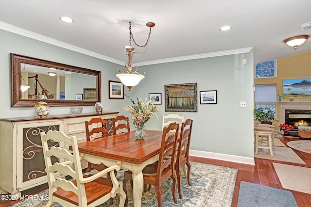 dining room with a premium fireplace, dark hardwood / wood-style flooring, and crown molding