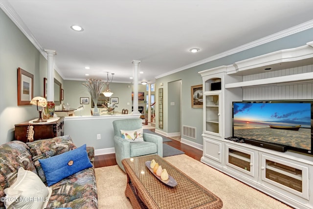 living room with decorative columns, ornamental molding, and hardwood / wood-style floors