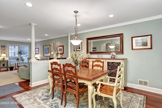 dining space featuring hardwood / wood-style flooring, crown molding, and ornate columns