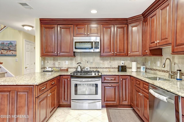 kitchen featuring light stone counters, stainless steel appliances, sink, and tasteful backsplash