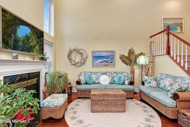 living room with a towering ceiling, a high end fireplace, and hardwood / wood-style floors