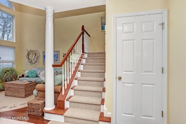 stairway with decorative columns and hardwood / wood-style floors