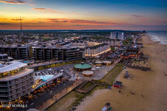 aerial view at dusk with a view of the beach and a water view