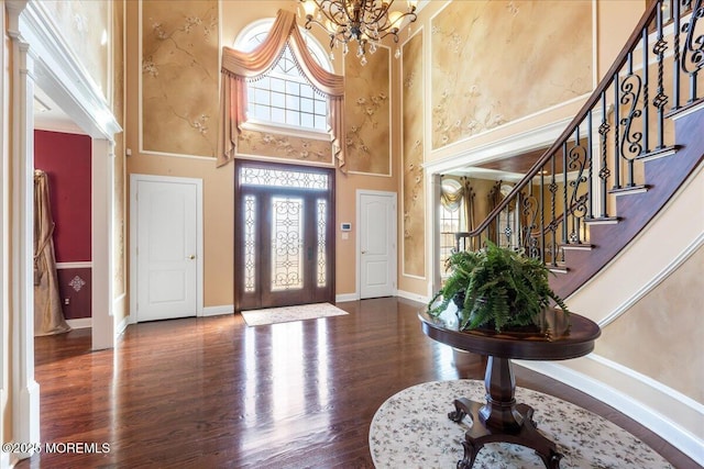 entryway with a notable chandelier, a towering ceiling, and dark wood-type flooring