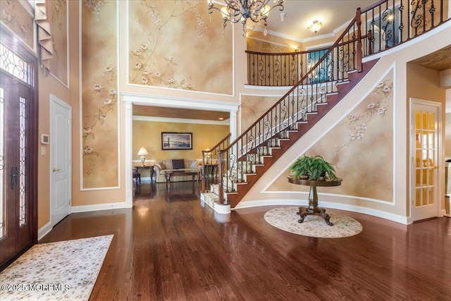 entrance foyer with an inviting chandelier, dark wood-type flooring, ornamental molding, and a high ceiling