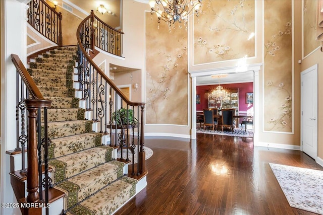 foyer with an inviting chandelier, decorative columns, dark hardwood / wood-style floors, and a high ceiling