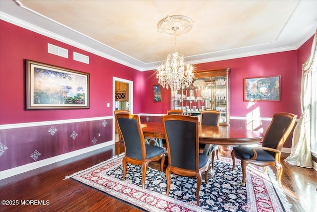 dining space featuring ornamental molding, wood-type flooring, and a notable chandelier