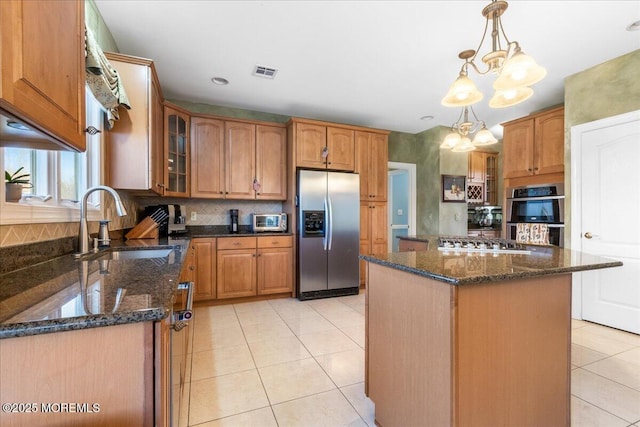 kitchen with a kitchen island, decorative light fixtures, sink, stainless steel appliances, and an inviting chandelier