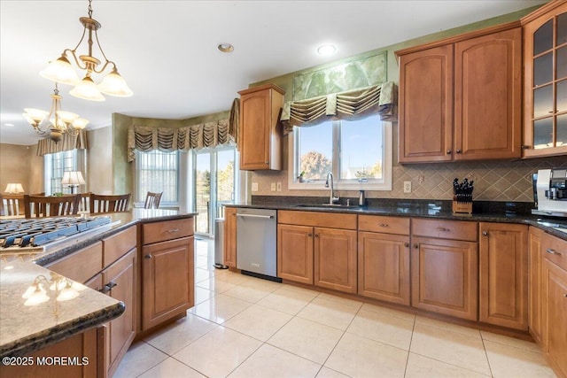 kitchen featuring sink, appliances with stainless steel finishes, a notable chandelier, decorative light fixtures, and dark stone counters