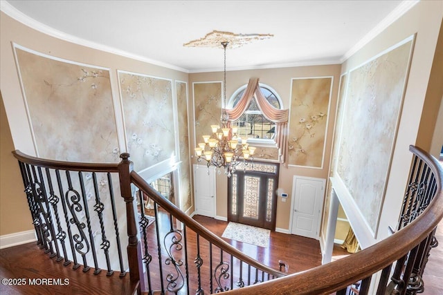 foyer with hardwood / wood-style flooring, crown molding, and a chandelier