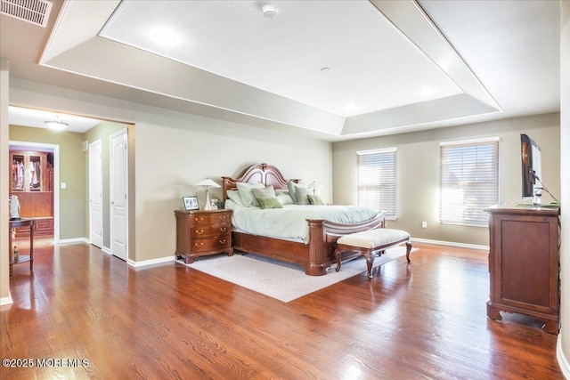 bedroom featuring a tray ceiling and wood-type flooring