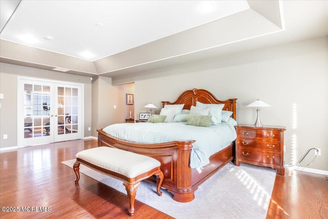 bedroom featuring french doors, a raised ceiling, and light hardwood / wood-style floors