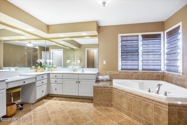 bathroom featuring tile patterned flooring, vanity, and a relaxing tiled tub