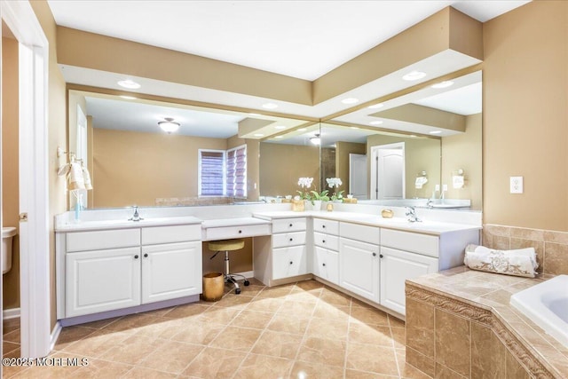 bathroom with vanity, tile patterned flooring, and tiled bath