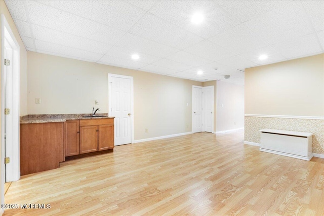 interior space featuring a paneled ceiling, sink, and light wood-type flooring