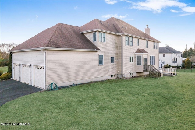 rear view of property featuring a garage and a lawn