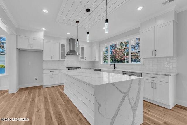 kitchen with hanging light fixtures, white cabinetry, a center island, and wall chimney exhaust hood