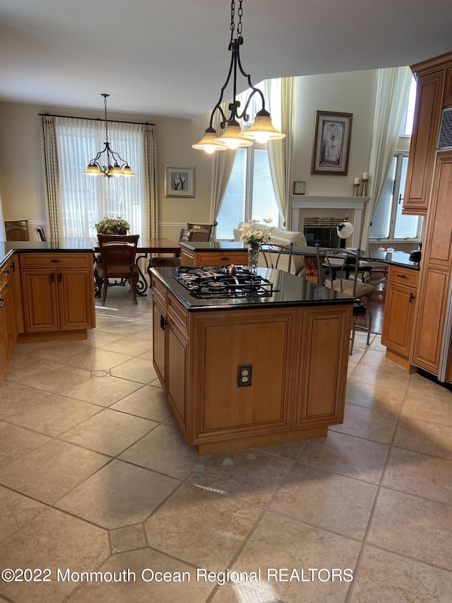 kitchen featuring a kitchen island, stainless steel gas cooktop, hanging light fixtures, and light tile patterned floors