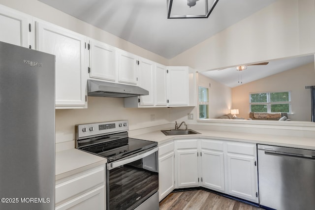 kitchen with white cabinetry, stainless steel appliances, vaulted ceiling, and sink