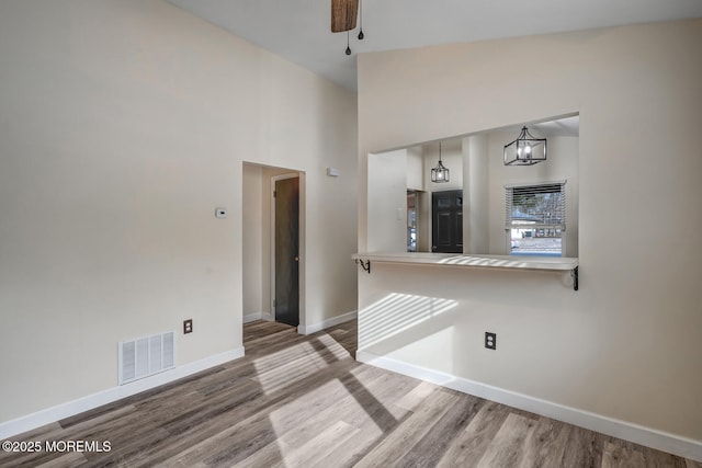 empty room featuring ceiling fan, hardwood / wood-style floors, and a towering ceiling