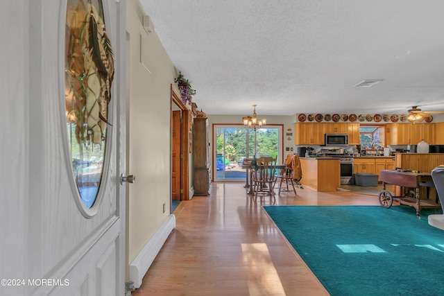 foyer with ceiling fan with notable chandelier, light hardwood / wood-style flooring, a textured ceiling, and baseboard heating