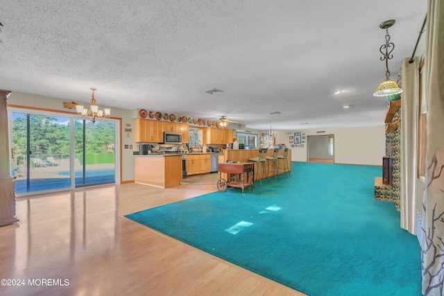 interior space featuring ceiling fan with notable chandelier, light hardwood / wood-style flooring, and a textured ceiling