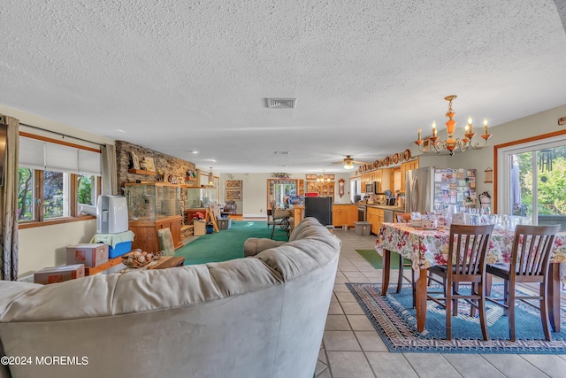 tiled living room with ceiling fan with notable chandelier and a textured ceiling