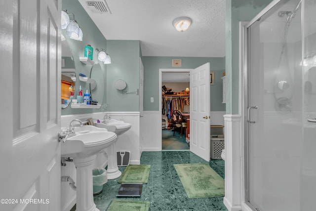 bathroom featuring sink, a shower with door, and a textured ceiling