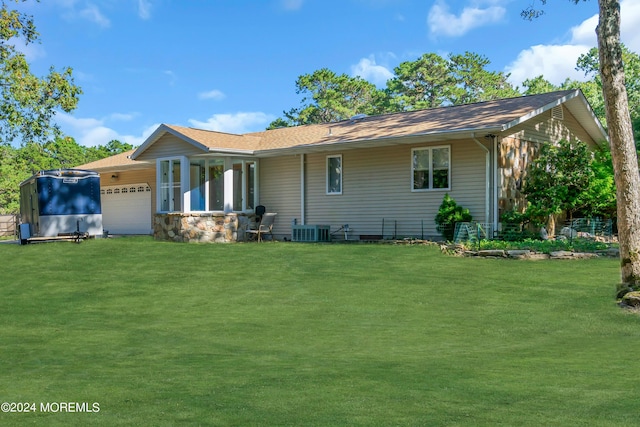 back of house featuring a garage, a yard, and central air condition unit