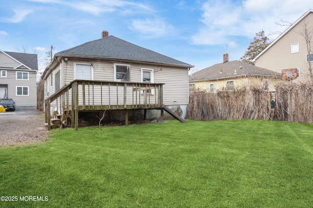 back of property with a wooden deck and a lawn