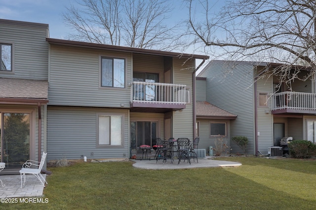 rear view of house with a patio, a balcony, central AC, and a lawn