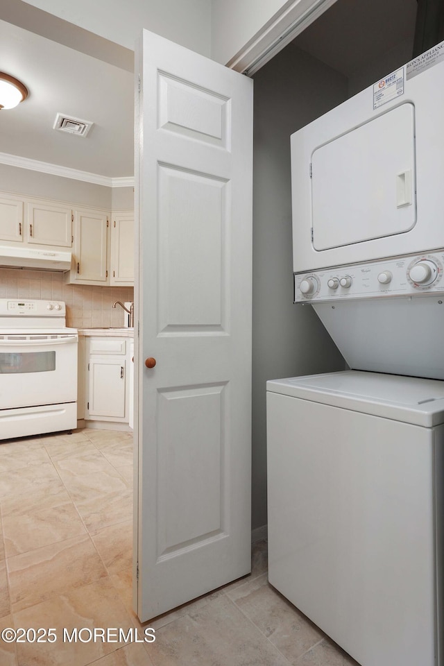 washroom featuring stacked washer and dryer and ornamental molding