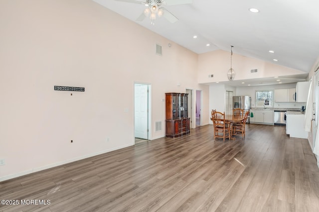 unfurnished living room with ceiling fan, high vaulted ceiling, and light hardwood / wood-style floors