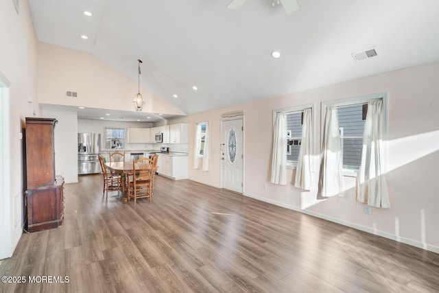 dining area featuring hardwood / wood-style floors, high vaulted ceiling, and ceiling fan