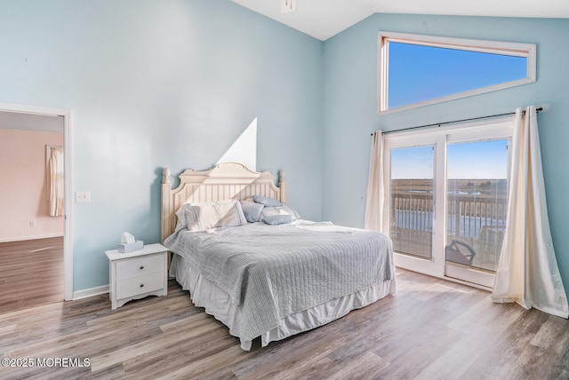 bedroom with access to exterior, high vaulted ceiling, and light hardwood / wood-style flooring