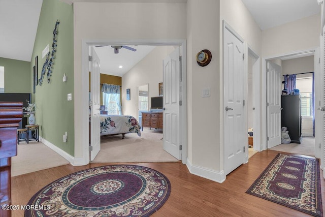 hallway featuring vaulted ceiling, light hardwood / wood-style floors, and a wealth of natural light