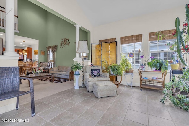 living room featuring light tile patterned floors, a high ceiling, and ornate columns