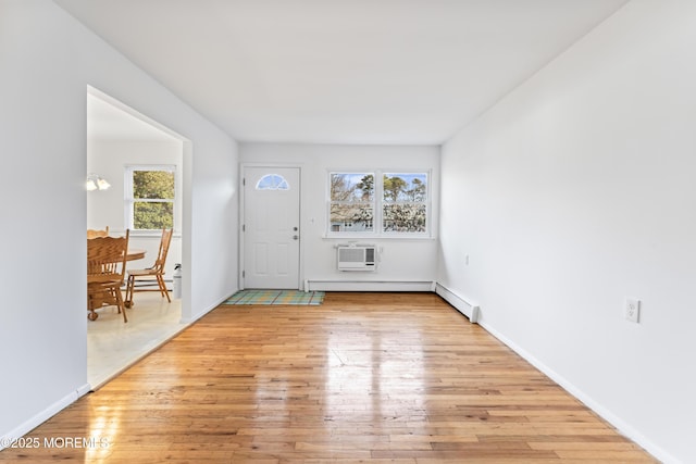 entryway with a baseboard radiator, a wall mounted AC, and light hardwood / wood-style flooring