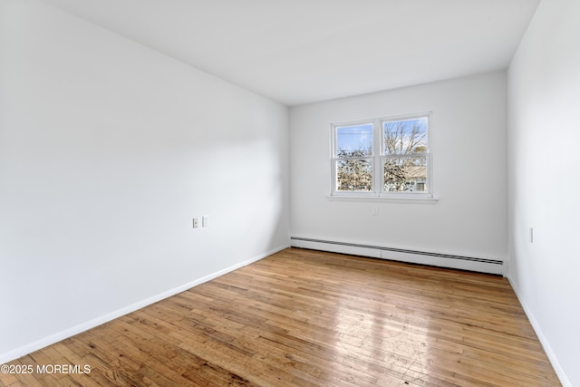 spare room featuring a baseboard heating unit and light hardwood / wood-style flooring