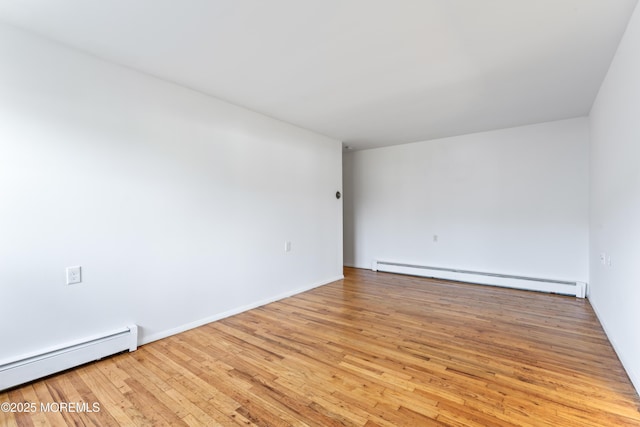 unfurnished room featuring baseboard heating and light hardwood / wood-style floors