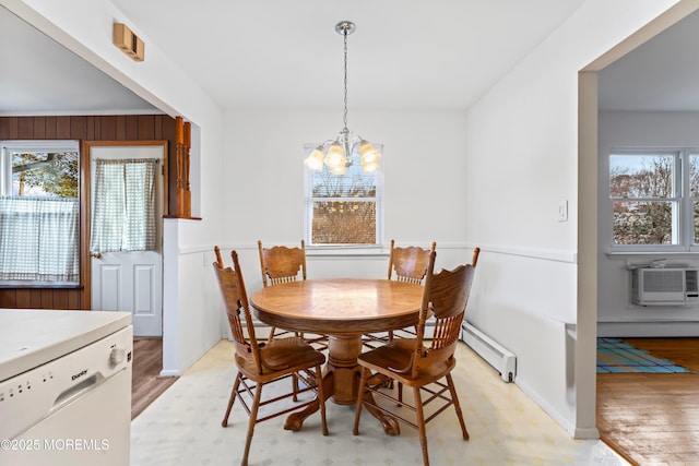 dining space featuring light hardwood / wood-style flooring, a notable chandelier, a baseboard radiator, and an AC wall unit