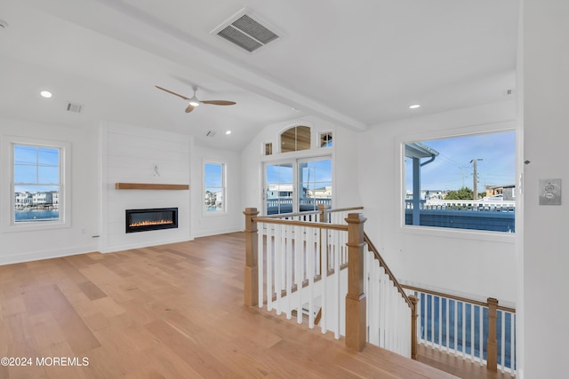 interior space featuring a fireplace, lofted ceiling with beams, light hardwood / wood-style floors, and ceiling fan