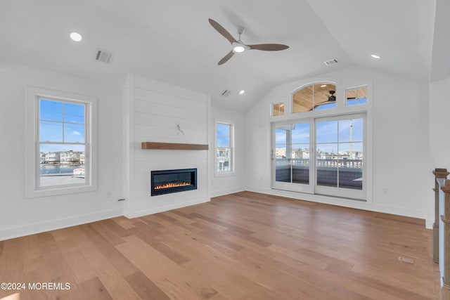 unfurnished living room featuring vaulted ceiling, ceiling fan, a fireplace, and light wood-type flooring