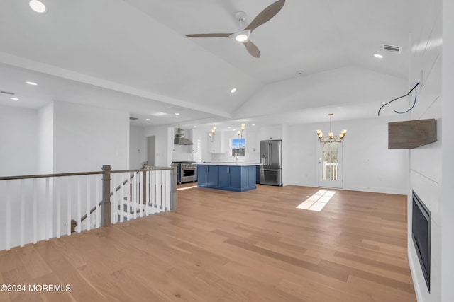 unfurnished living room with lofted ceiling, ceiling fan with notable chandelier, and light hardwood / wood-style flooring