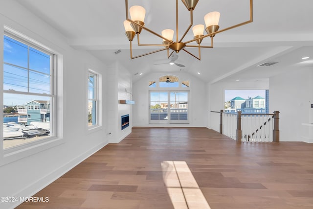 unfurnished living room featuring wood-type flooring, vaulted ceiling, a fireplace, and a chandelier