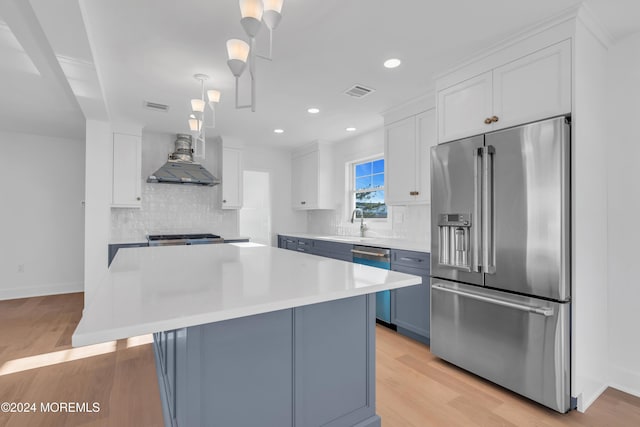 kitchen with blue cabinets, appliances with stainless steel finishes, white cabinets, and decorative light fixtures