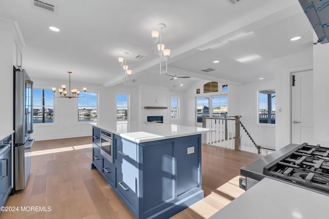 kitchen with a kitchen island, blue cabinets, hanging light fixtures, stainless steel appliances, and light wood-type flooring